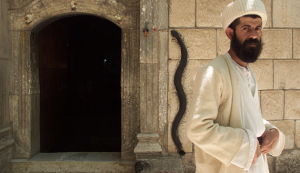 YEZIDI MONK BABA CHAWISH POSES IN FRONT OF ENTRANCE TO THE LALISH TEMPLE.
